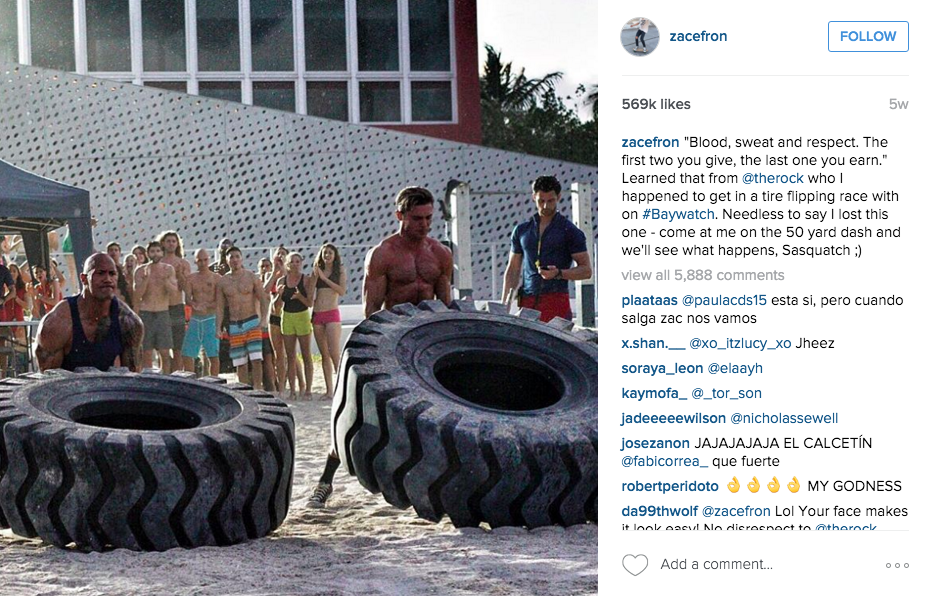 Zac Efron Instagram Pic of him vs the Rock in a tire flip contest on the set of Baywatch.